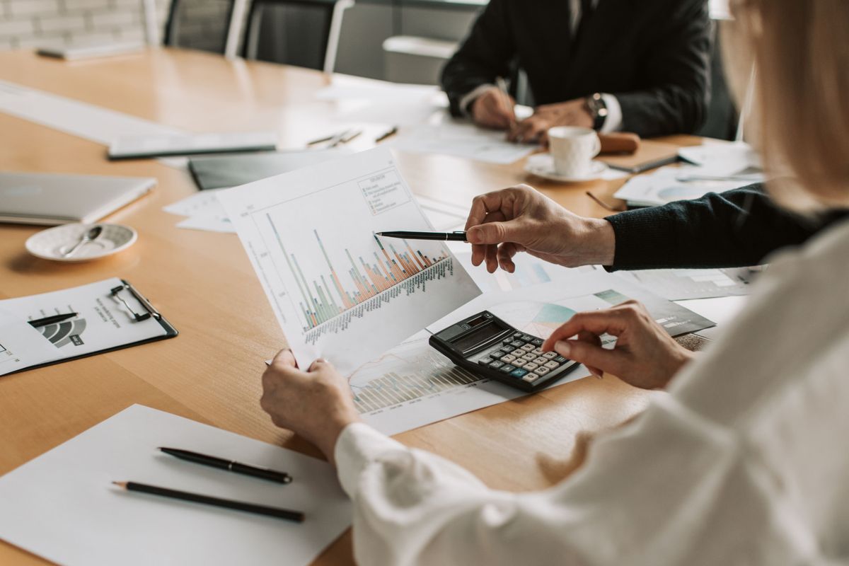 Consultants reviewing charts and calculating fees at a boardroom table