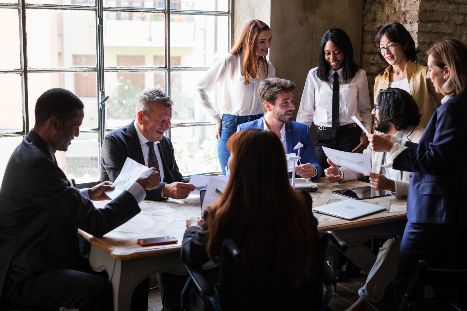 Diverse team of business professionals collaborating around a table reviewing documents and charts