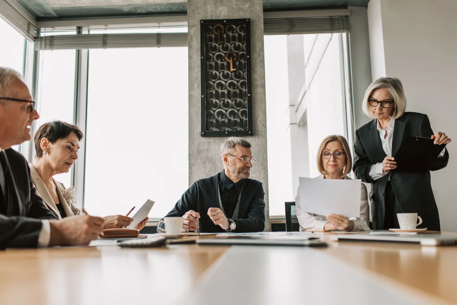 Executive team reviewing documents together around a conference table in a bright corner office