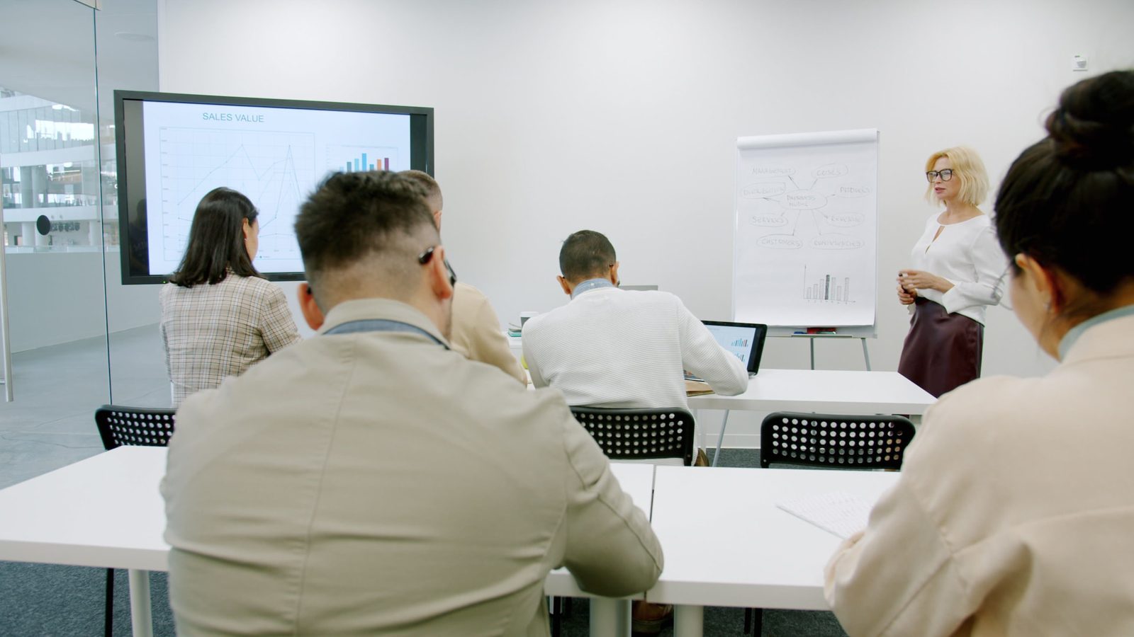 Team seated in a training room reviewing sales value charts with a leader at the whiteboard