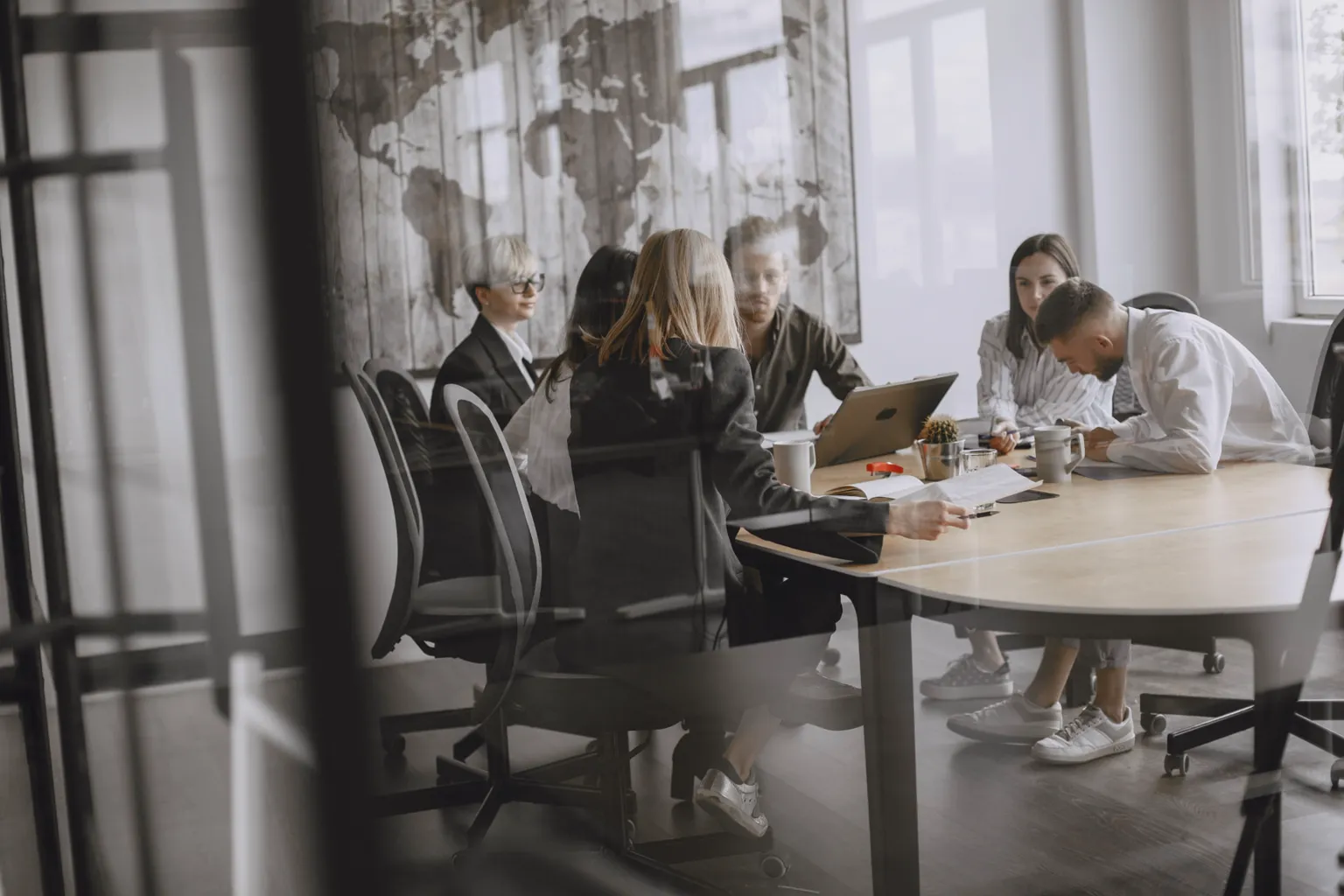 A consulting team reviewing documents and a laptop around a conference table