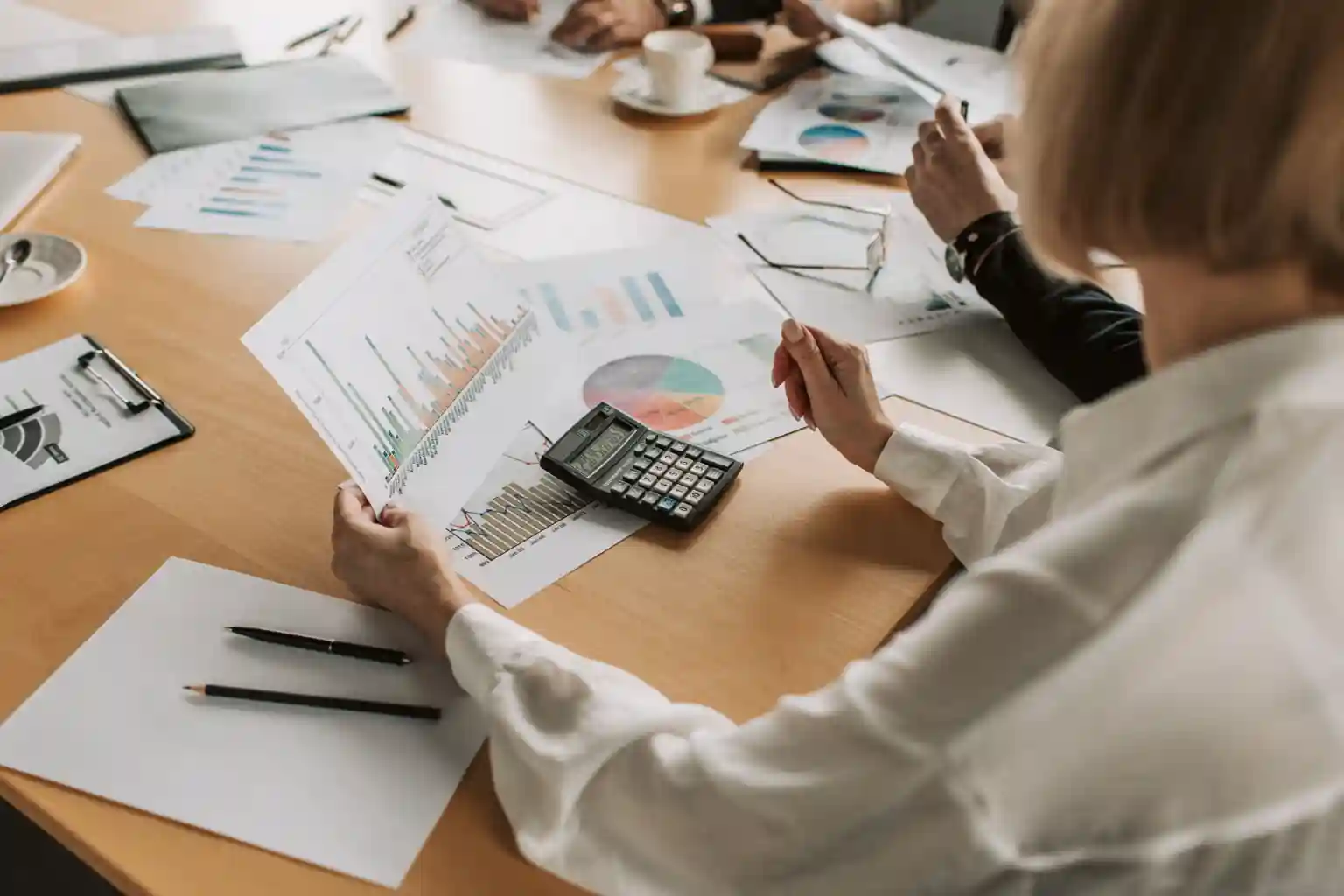 Consultants reviewing revenue charts and a calculator across a meeting table